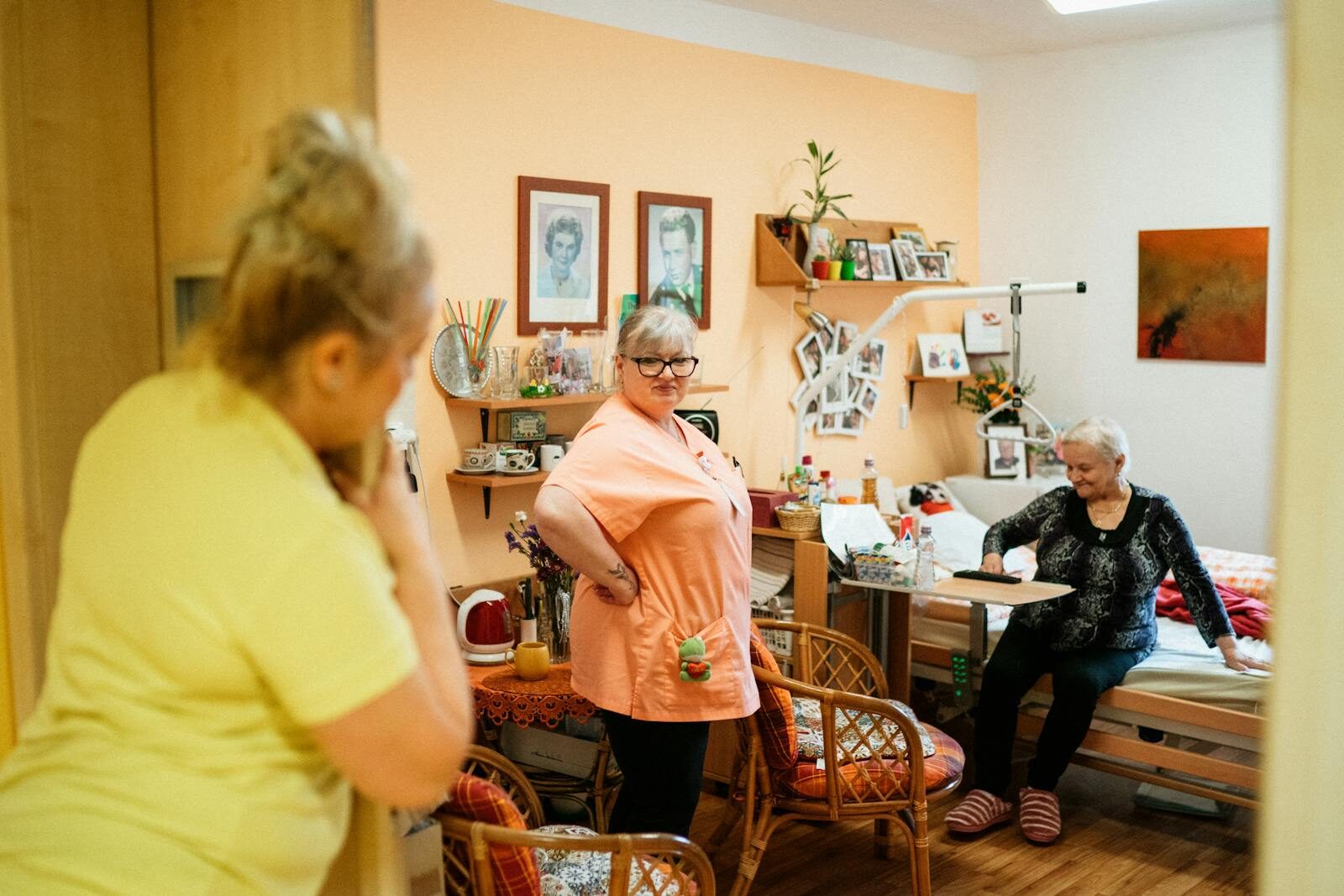 Caregivers interacting with a senior woman in a cozy retirement home in Karviná, Czech Republic.
