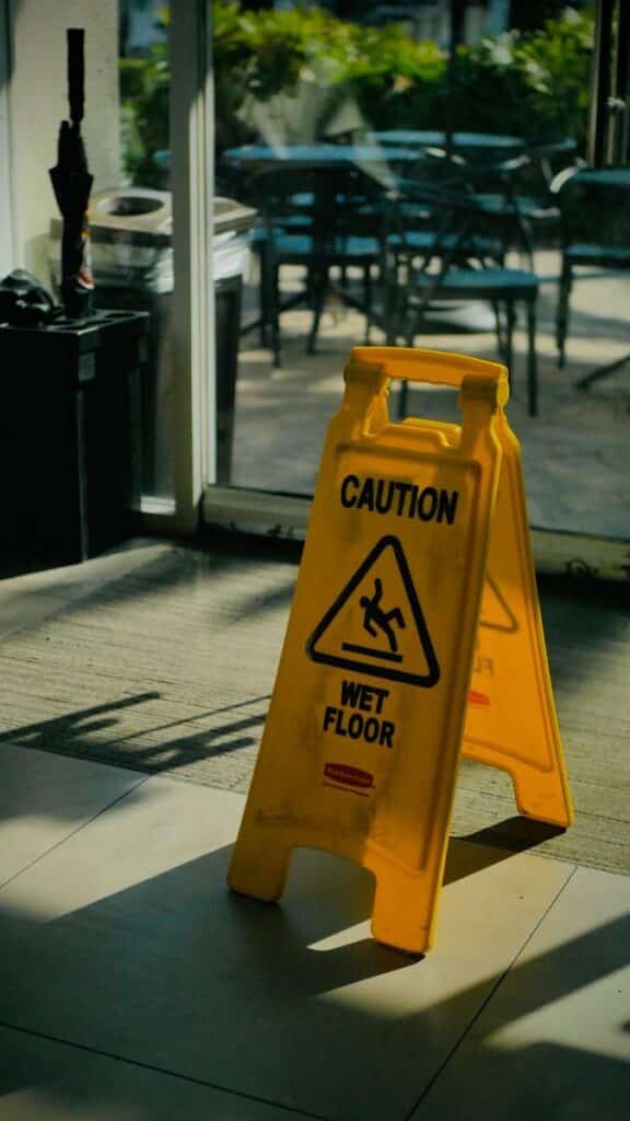 Yellow caution wet floor sign in bright indoor space, highlighting safety warning.