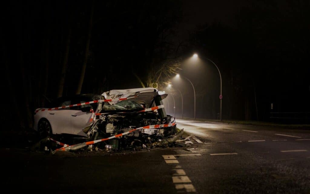 A wrecked car after a crash on a dimly lit street in Berlin at night.