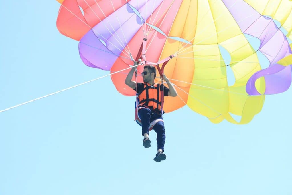 Current image: man in black and red jacket and blue denim jeans riding yellow parachute