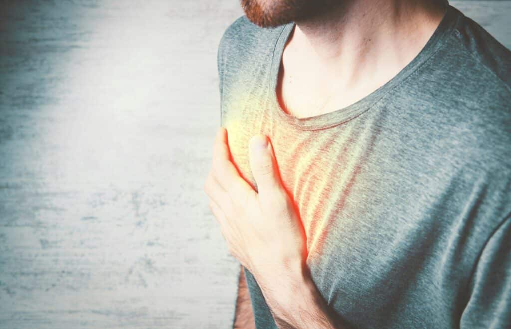 Current image: a man holding his chest with his hands