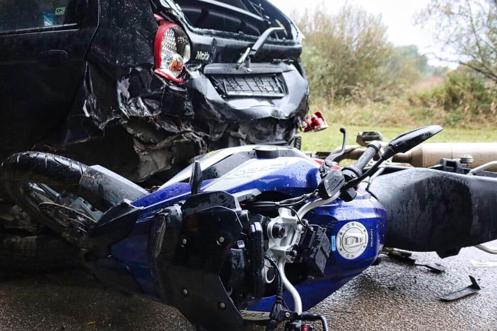 Damaged motorcycle lying beside a crushed car after a motorcycle accident on a South Carolina road