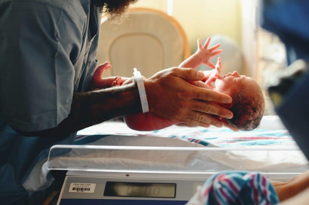 Current image: person wearing gray shirt putting baby on scale